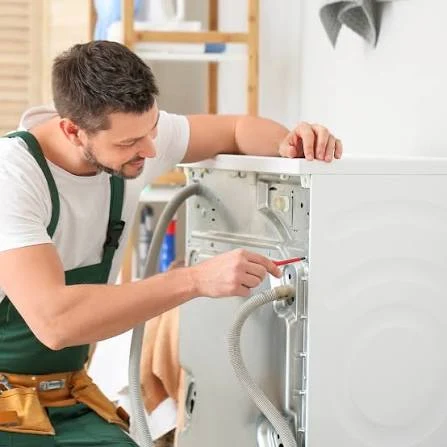 Technician inspecting hoses and fittings behind a washing machine