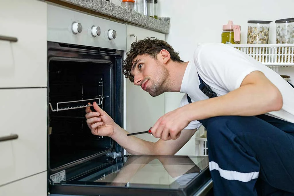 Technician examining the inside of an open built-in oven